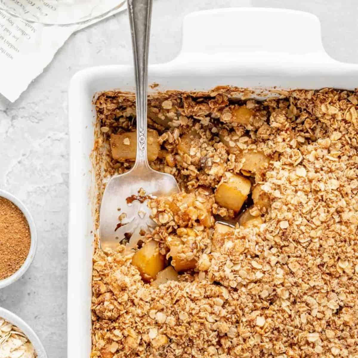Photo of apple crisp being scooped out of a pan.